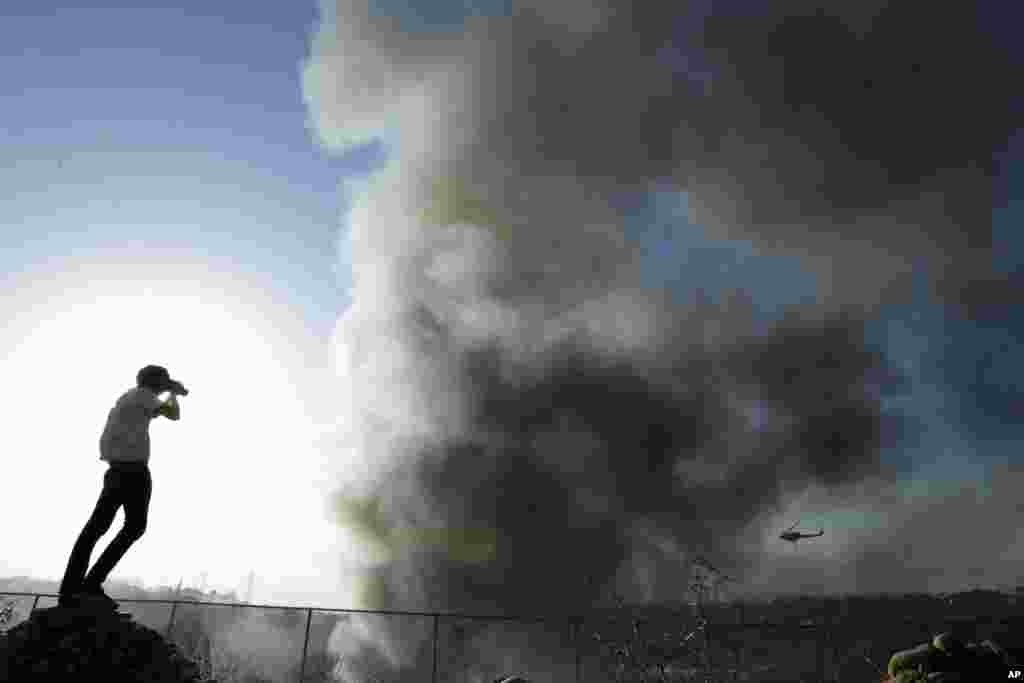 Travis Lowell takes a picture as smoke from wildfires rises in Carlsbad, California, May 14, 2014.