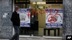 Man passes entrance of a store that buys gold vandalized with Greek word "thievess," Nicosia, Cyprus, March 25, 2013.