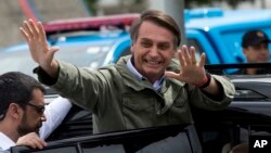 Jair Bolsonaro waves after voting in the presidential runoff election in Rio de Janeiro, Brazil, Sunday, Oct. 28, 2018. (AP Photo/Silvia izquierdo)