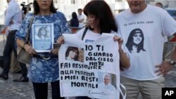 Reanta Grattani, who claims to be a friend of the Orlandi family, center, holds a t-shirt with the pictures of Emanuela Orlandi and Pope Francis outside the Vatican, Saturday, July 20, 2019. 