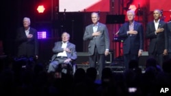 Former Presidents from right, Barack Obama, Bill Clinton, George W. Bush, George H.W. Bush and Jimmy Carter place their hands on their heart for the national anthem at the opening of a hurricanes relief concert in College Station, Texas, Oct. 21, 2017.