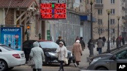 People walk past a currency exchange rate display in central Moscow, Dec. 1, 2014.