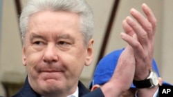 Moscow Mayor Sergei Sobyanin applauds as United Russia party and government-linked trade unions take to the streets to mark May Day in Moscow, Russia, Sunday, May 1, 2011. Thousands of Communists, members of Russia's main political parties and opposition 