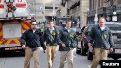 Para petugas Biro Penyidikan Federal (FBI) segera menyelidiki situasi di lokasi kejadian ledakan bom, dekat garis finish lomba marathon Boston, Massachusetts (15/4). 