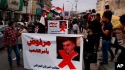 Protesters hold posters showing Iraq's Prime Minister-designate Mohammed Tawfiq Allawi with Arabic that reads, "Rejected by order of the people," during a rally in Baghdad, Iraq, March 1, 2020.