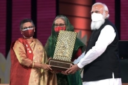 Indian Prime Minister Narendra Modi gives the Gandhi Peace Prize, awarded posthumously to Bangladesh founder Sheikh Mujibur Rahman, to his daughters, Bangladesh Prime Minister Sheikh Hasina, center, and Sheikh Rehana, in Dhaka, March 26, 2021.