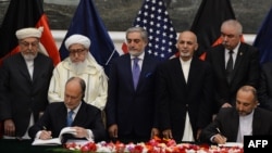 Pejabat keamanan Afghanistan Hanif Atmar (kanan) dan Dubes AS James Cunningham (kiri) menandatangani perjanjian keamanan disaksikan PresidenAfghanistan Ashraf Ghani di Kabul, Selasa (30/9).