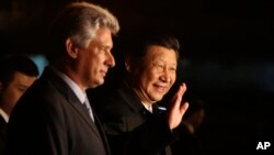 China's President Xi Jinping, center, waves to the press accompanied by Cuba's Vice President Miguel Diaz-Canel, left, at his arrival at the Jose Marti International Airport in Havana, Cuba, July 21, 2014.