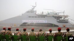 FILE - Members of Iran's Revolutionary Guard sit in front of a newly inaugurated high-speed warship, in the northern Persian Gulf port city of Bushehr, Iran, Sept. 13, 2016.