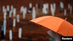 Seorang perempuan mengenakan masker dan pelindung wajah berdoa saat pemakaman seorang kerabat di pemakaman khusus jenazah pasien Covid-19 di TPU Pondok Rangon, Jakarta, 24 September 2020. (Foto: Reuters)