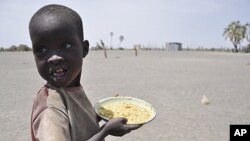 A young boy walks away with his food from a government sponsored feeding center in central Turkana, Kenya, August 30, 2011