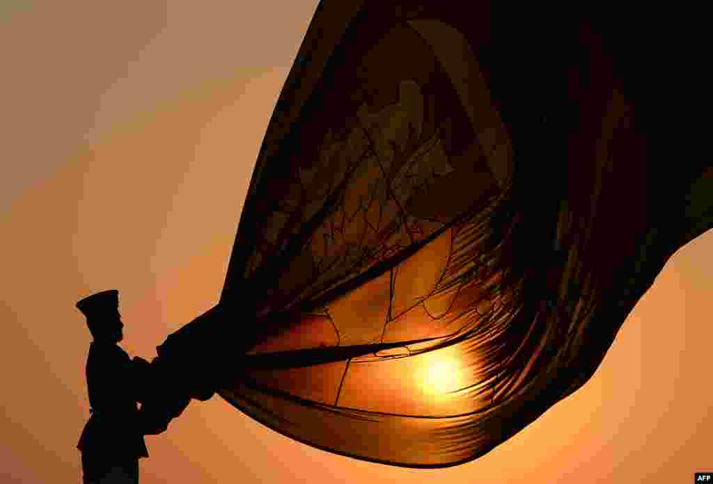 A Sri Lankan Air force officer hold the national flag as it is lowered during a daily ceremony held at sunset at the Galle Face Green promenade in Colombo.