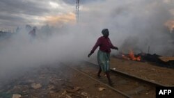 Une femme passe devant une cabane incendiée près d'un chemin de fer par des manifestants dans le bidonville de Kibera à Nairobi le 12 août 2017.
