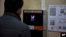 FILE - A man tries out a facial recognition toilet paper dispenser at a toilet in the Temple of Heaven park in Beijing, China, March 21, 2017.