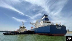 In this photo provided by Egypt's Suez Canal Authority, a tugboat pushes the Malta-flagged Seavigour after it suffered a mechanical malfunction at the 12 kilometers (7.5 miles) mark of the canal, Egypt, June 4, 2023