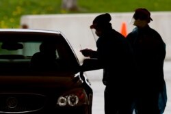 FILE - Medical workers test a local resident at a drive-thru COVID-19 testing site in Waterloo, Iowa, May 1, 2020.