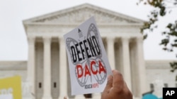 FILE - A sign is held aloft as people rally outside the Supreme Court in support of the Deferred Action for Child Arrivals program, Nov. 12, 2019, in Washington.