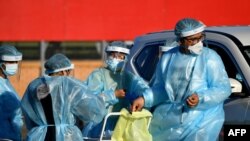 FILE - Health workers take swab samples from residents at a COVID-19 drive-through testing site in western Sydney, Aug. 4, 2021. 