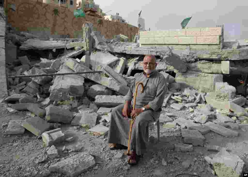 A Palestinian man sits near the destroyed house of Hussam Kawasma, one of three Palestinians identified by Israel as suspects in the killing of three Israeli teenagers. His home was demolished by the Israeli army in the West Bank, city of Hebron, Aug. 18, 2014.