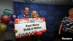 Paul White, from Ham Lake, Minnesota, stands with his partner Kim VanReese as he holds a check for his $149.4 million portion of a $448.4 million Powerball jackpot prize. 