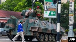 Un homme passe un char de l'armée zimbabwéenne où les soldats régulent le trafic routier, à Harare, au Zimbabwe, le 15 novembre 2017. 