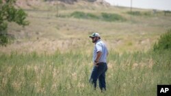 Cole Gustafson, a water resource administrator for the city of Greeley walks in a meadow to find a well head on the Terry Bison Ranch near Carr, Colorado. (AP Photo/David Zalubowski)