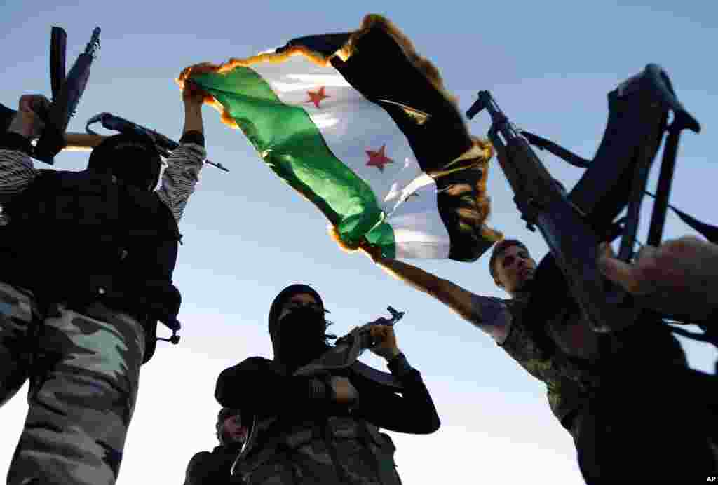 Free Syrian Army members raise their weapons and a revolutionary flag during a training session on the outskirts of Idlib, Syria, June 7, 2012.