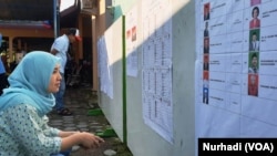 Seorang pemilih memeriksa daftar legislatif yang dipasang di sebuah TPS di Sleman, DIY dalam Pemilu 2019. (Foto:VOA/Nurhadi)