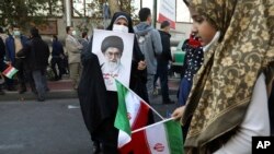 FILE - A demonstrator holds a portrait of the Iranian Supreme Leader Ayatollah Ali Khamenei as a girl holds the country's national flag in a rally in front of the former U.S. Embassy commemorating the anniversary of its 1979 seizure in Tehran, Iran, Nov. 