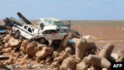 Mobil-mobil menumpuk di atas pemecah gelombang dan puing-puing bangunan yang hancur akibat banjir bandang setelah badai Mediterania "Daniel" menghantam kota Derna di timur Libya, pada 14 September 2023. (Foto: AFP)