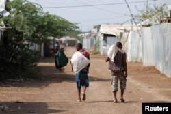 FILE - Wanaume wakibeba mifuko ya chakula cha msaada katika kambi ya wakimbizi ya Kakuma kaskazini mwa Kenya, March 6, 2018.