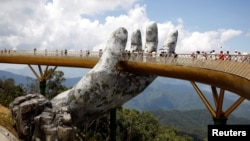 Tourists walk past giant hand structure on the Gold Bridge on Ba Na hill near Danang City, Vietnam August 1, 2018. (REUTERS/Kham)