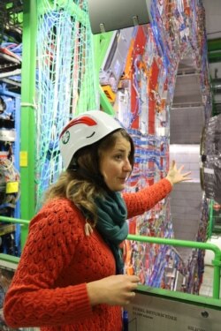 Ludivine Ceard, physicist with the CMS Collaboration, gestures at the Compace Muon Solinoid - one of the experiments at CERN, in Geneva, looking for the tiniest particles of matter. (Courtesy Robert Gumm.)