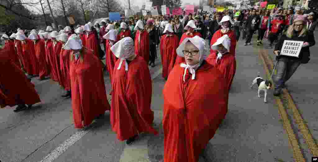 Members of the &quot;Texas Handmaids&quot; lead a women&#39;s march to the Texas State Capitol on the one-year anniversary of President Donald Trump&#39;s inauguration, Jan. 20, 2018, in Austin, Texas. The costumes are a nod to &quot;The Handmaid&#39;s Tale,&quot; a novel and television series.