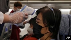 Stewardesses take temperatures of passengers as a preventive measure for the coronavirus on an Air China flight from Melbourne to Beijing before it land at Beijing Capital International Airport in China, Feb. 4, 2020.