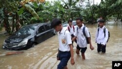 Para pelajar berjalan di jalan yang tergenang banjir di Jakarta, 25 Februari 2020. 