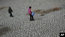 People walk on a dried up pond at Hanzhuang village in Tangyin county in central China's Henan province (File Photo)