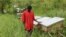 Latib Kalema stands beside the bee hives that have been preventing elephants from crossing to raid his crops, September 28, 2012. (H. Heuler/VOA)