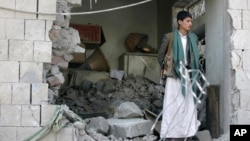 A Yemeni stands guard at the damaged residence of the Iranian ambassador after a car bomb attack in Sanaa, Yemen, Dec. 3, 2014.