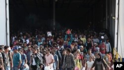 Migrants and refugees disembark from a ferry arriving from the northeastern Greek island of Lesbos, Piraeus, Greece, Sept. 6, 2015. 