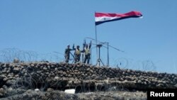 Syrian forces of President Bashar al Assad are seen celebrating on al-Haara hill in Quneitra area, Syria, July 17, 2018. 
