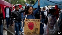FILE - A demonstrator with a banner that in Spanish reads "Justice 43 Ayotzinapa" in reference to the 43 missing students from a rural teachers college marches in protest, marking 30 months since their disappearance, in Mexico City.