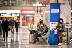 People wear masks as they wait inside Central train station, in Milan, Italy, March 8, 2020.