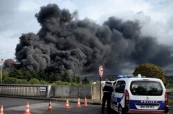 A policeman stands on a blocked road in Le Petit-Quevilly on September 26, 2019 as smoke billows from a Lubrizol factory classified Seveso high-threshold site on fire in Rouen. Residents of twelve towns including Rouen have been asked to stay at…
