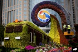 Pekerja di peron memasang bunga pada dekorasi berbentuk kereta di Beijing, Selasa, 23 April 2019. (Foto: AP)