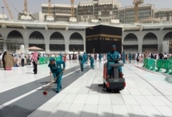 Workers clean the Grand Mosque, during the minor pilgrimage, known as Umrah, in the Muslim holy city of Mecca, Saudi Arabia, Monday, March 2, 2020.