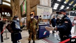 FILE - Police officers and soldiers check passengers leaving from Milan main train station, March 9, 2020. 