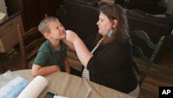 Mendy McNulty swabs the nose of her son, Andrew, 7, Tuesday, July 28, 2020, in their home in Mount Juliet, Tenn. (AP Photo/Mark Humphrey)