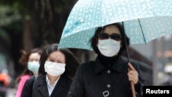 Pedestrians wearing medical masks walk on the street outside National Taiwan University Hospital in Taipei, April 26, 2013. A 53-year-old Taiwan businessman contracted the H7N9 strain of bird flu while travelling in China, the first reported case outside of mainland China. 