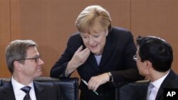 Dari kiri: Menteri Luar Negeri Jerman Guido Westerwelle, Kanselor Angela Merkel dan Menteri Perekonomian Jerman Philipp Roesler, berbincang setibanya di ruang sidang kabinet untuk pertemuan mingguan di Berlin, Jerman (6/12). Kabinet Jerman telah menyetujui misi pengiriman misil patriot ke Turki.